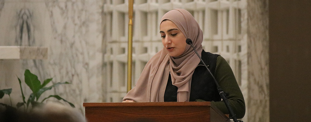 A woman stands behind a podium and speaks