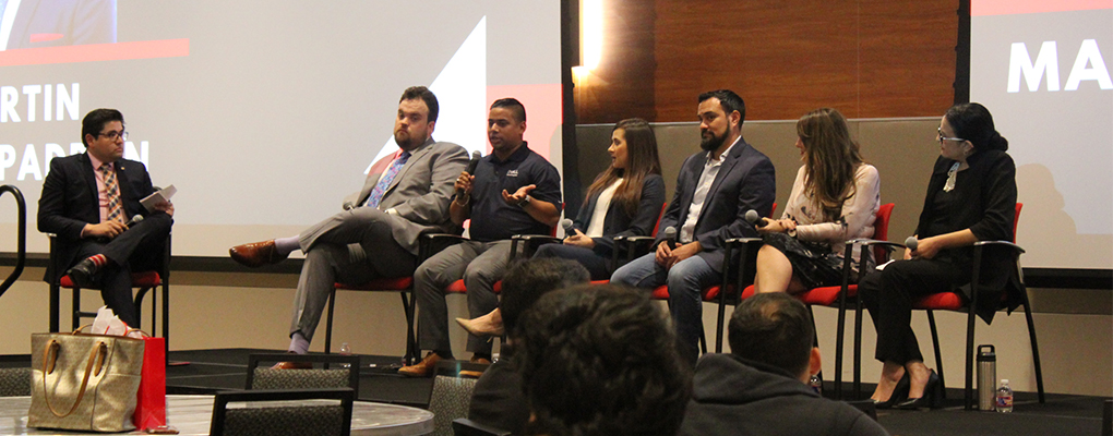 Panelists sit on stage while a moderator speaks into a microphone