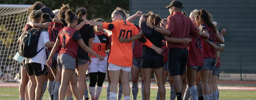 The women's soccer team gathers for a team huddle