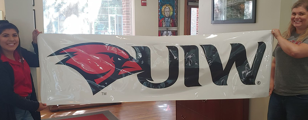 UIW employees pose for a photo holding up a UIW branded banner