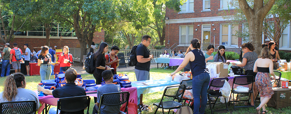 UIW students stand on Dubuis Lawn, enjoying food and company