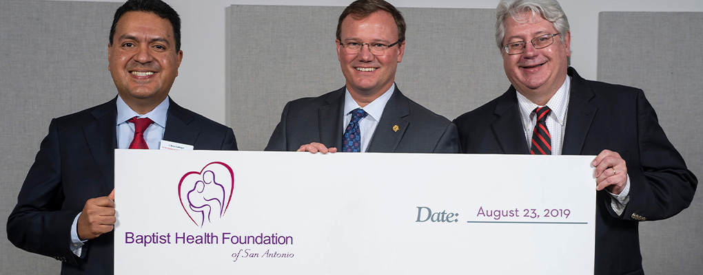 Chris Gallegos, Dr. Thomas Evans and Jon Gillespie hold a large check and smile at the camera 