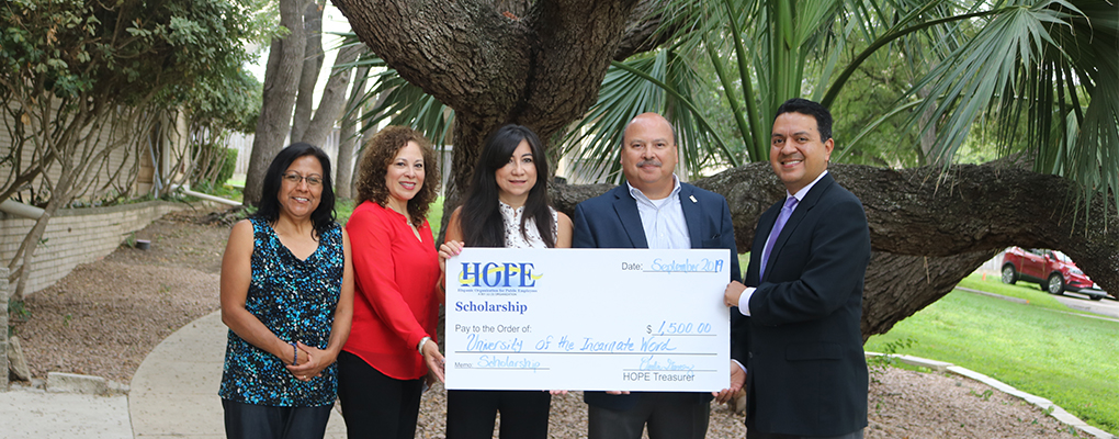 Members of the HOPE Organization stand with UIW representatives holding a large check and smiling at the camera