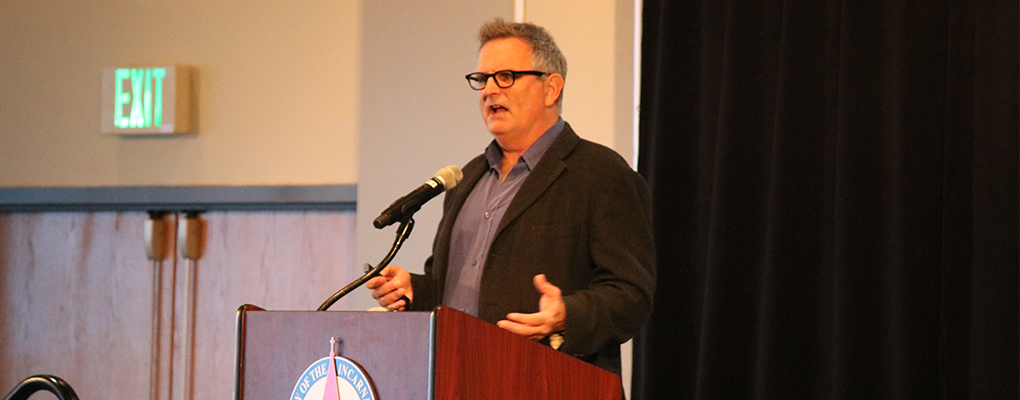 Gilbert King stands behind a podium and delivers his lecture