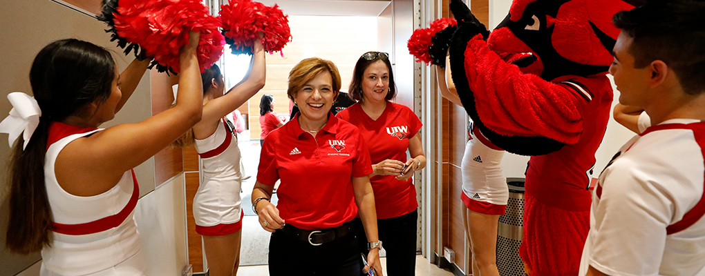 A UIW employee enters a room as she is cheered on by cheerleaders