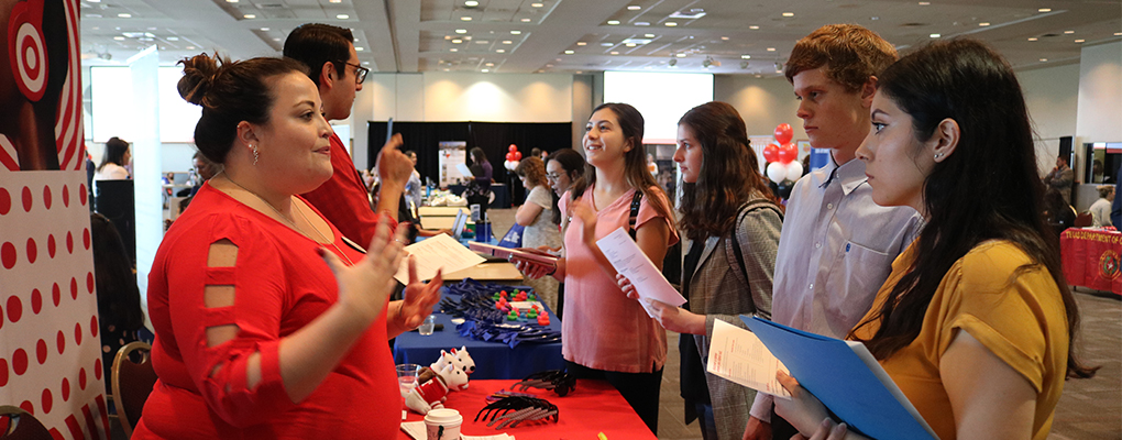 a group of students converse with employers at a job fair