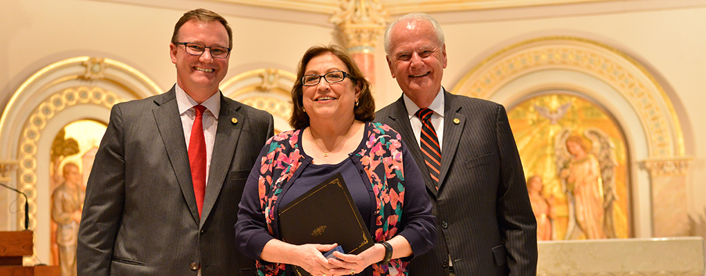 Mary Ann de la Garza holds her award and poses for a photo next to Dr. Evans and Charles Lutz