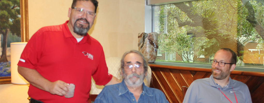 Three men pose for a photo and look at the camera