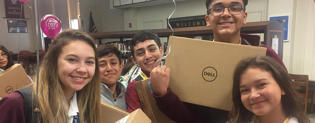 St. Anthony Catholic High School students smile while holding new laptop boxes