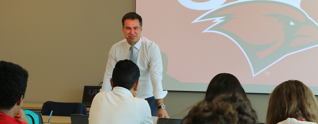 State Rep. Roland Gutierrez leans over a table and speaks to students