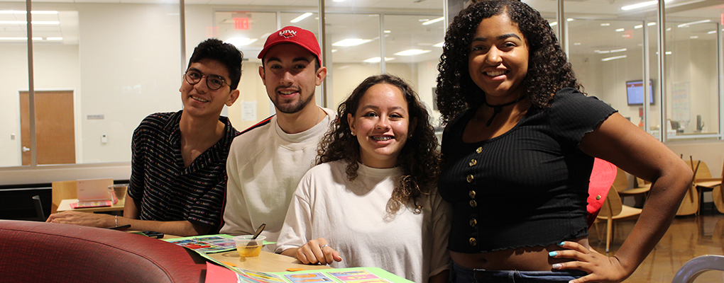 Four students smile at the camera and pose for a photo together