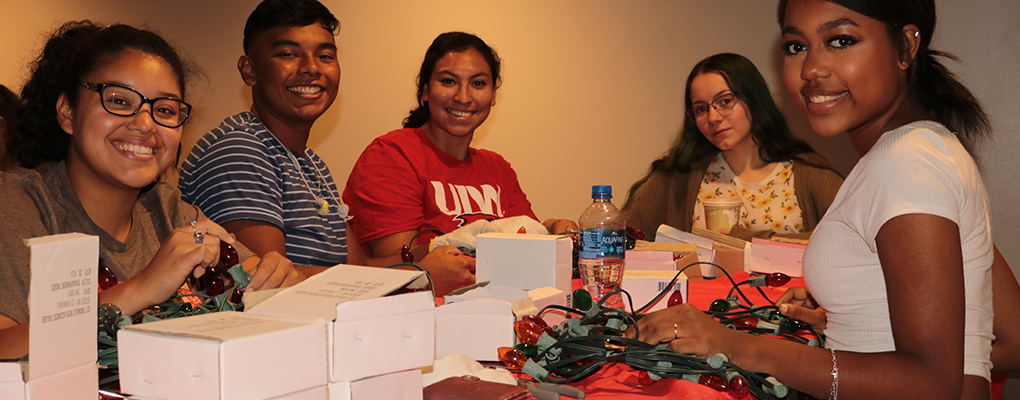 students stand around a table and replace broken Christmas lights