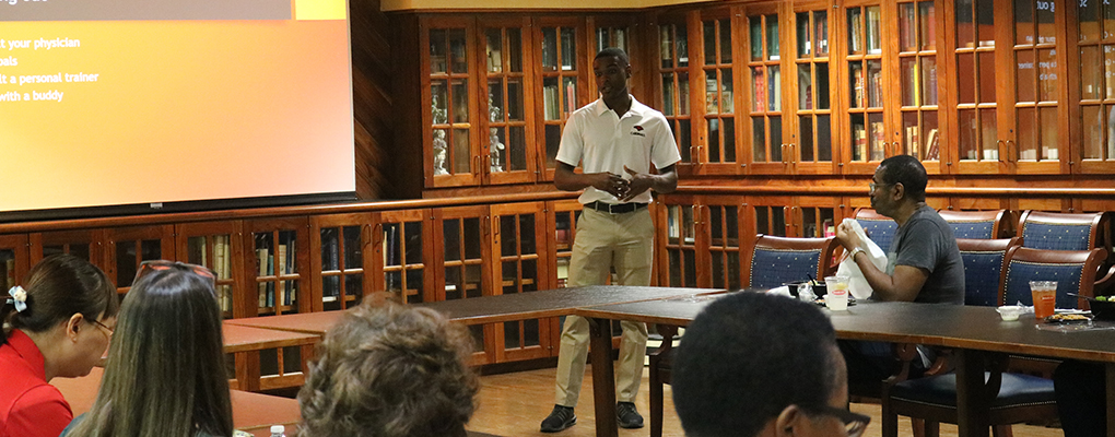 Randalle Williams-Diaz stands at the front of the room while lunch and learn attendees listen to his presentation