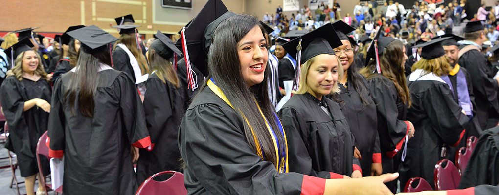 UIW graduates dressed in their caps and gowns stand for mass 