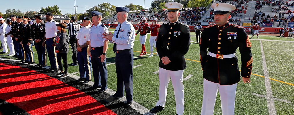 Veterans in uniform stand on the football field