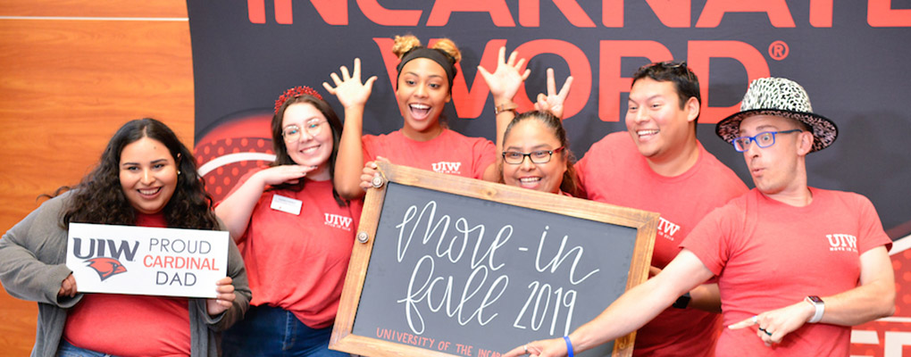 Residence Life staff and volunteers pose for a photo with props at the photobooth at Move-In Day