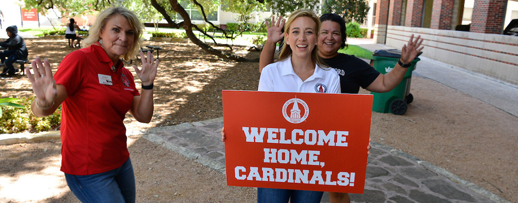UIW staff members hold a sign that says 'Welcome Home, Cardinals'