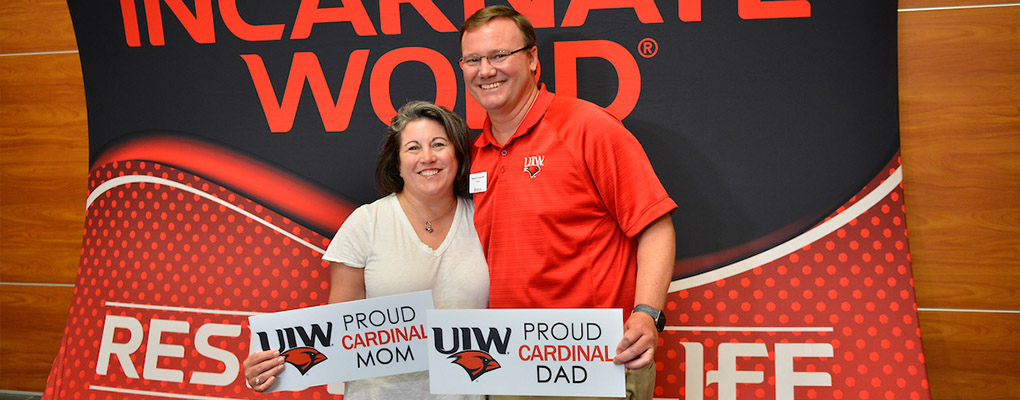Dr. and Mrs. Evans hold UIW Mom and Dad signs at the Move-In Day photobooth