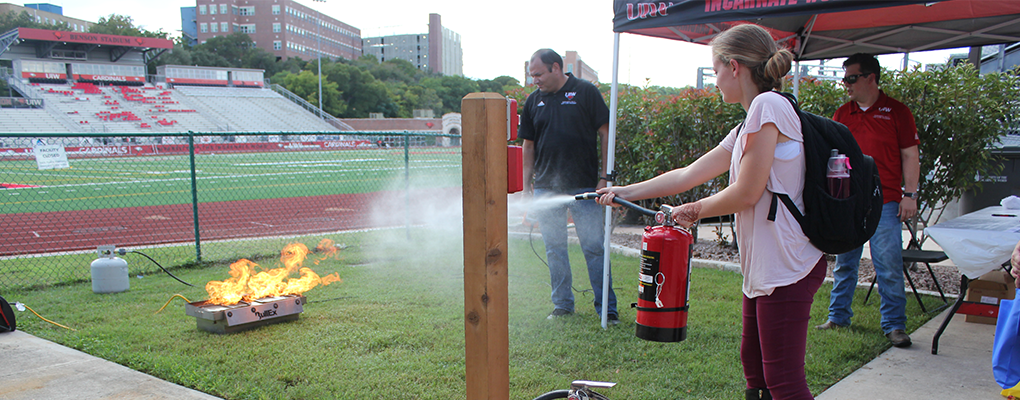 A UIW student uses a fire extinguisher to put out a small fire in a fire extinguisher training at National Night Out