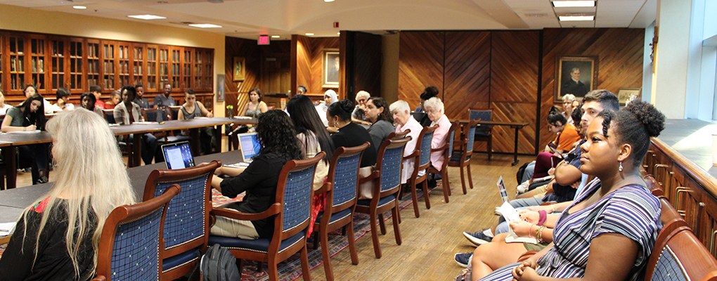 Event attendees sit in a row listening to the presentation