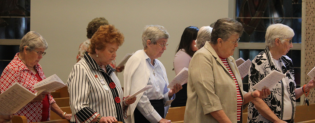 CCVI sisters stand in a chapel and follow along the parts of the mass