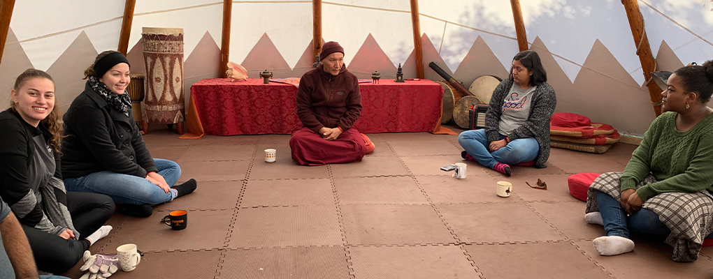 UIW students sit on the floor with a Buddhist monk