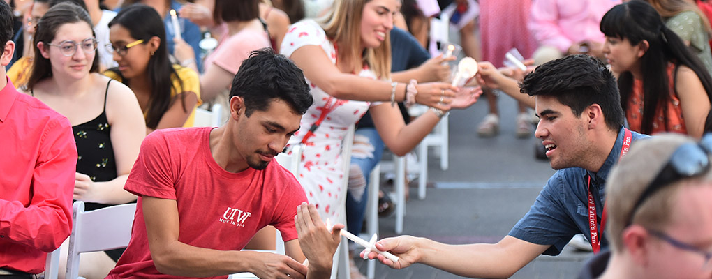 Freshmen students help light one another's candles at Pinning Ceremony 