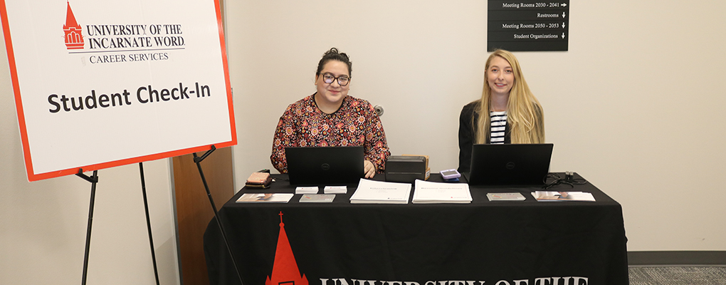 UIW employees sit at a check-in table