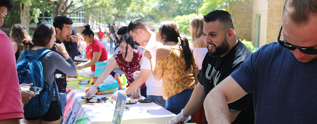 Salsa competition attendees exchange samples of various salsas from across a table