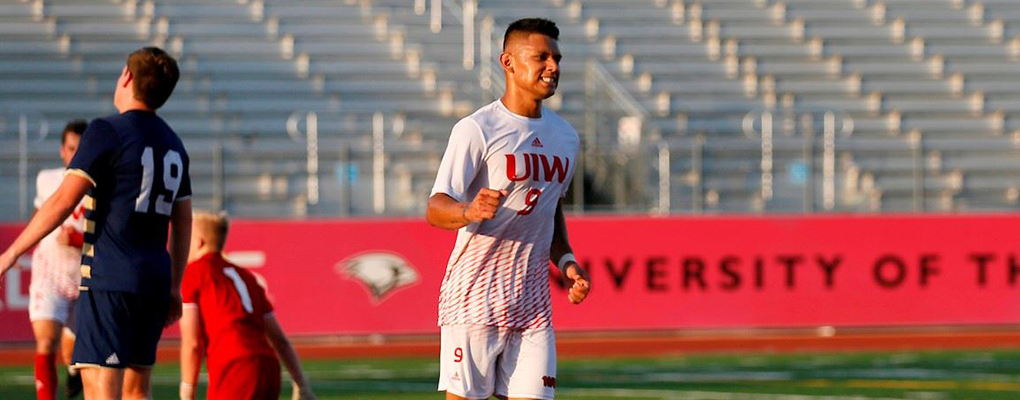 A smiling men's soccer player runs down the field