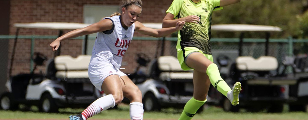 A UIW women's soccer player runs down the field while trying to keep control of the ball as a member of the opposing team tries to take it