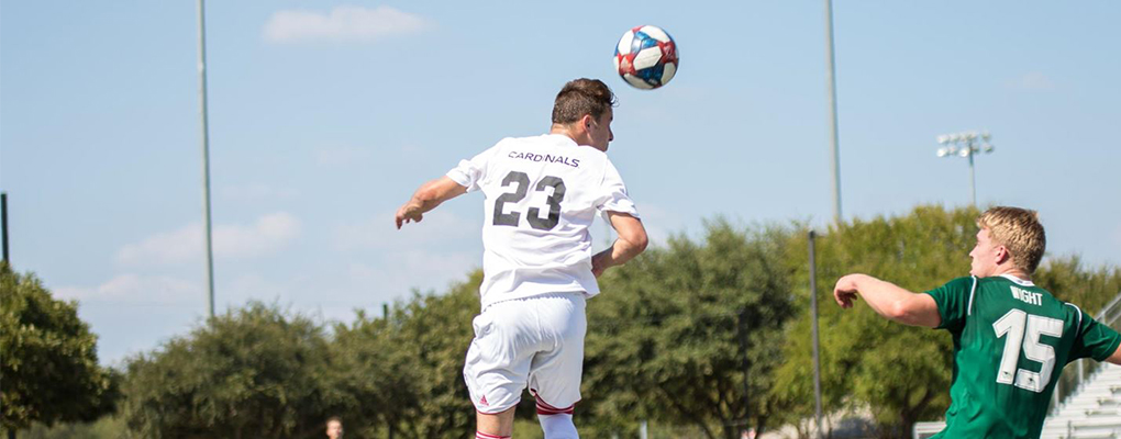 A men's soccer player jumps to hit a soccer ball with his head