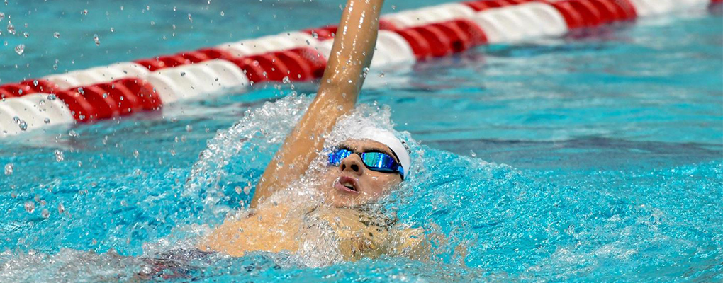 A UIW swimmer does the backstroke in a pool