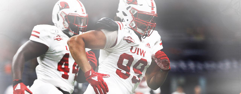 Two UIW football players in uniform run down the field