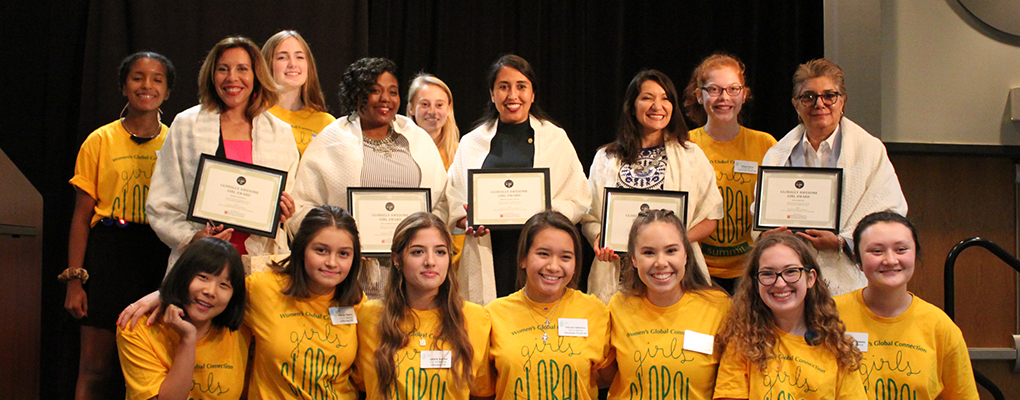 A group of girls wearing yellow t-shirts pose for a group photo together