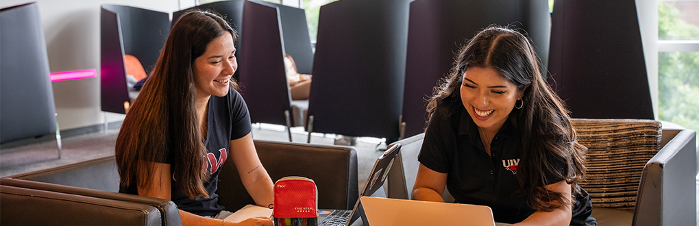 Two students sitting in the SEC while on their computers