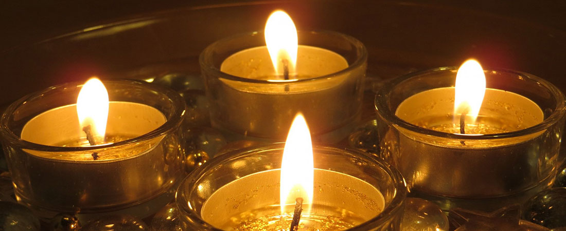 Photo of four white candles burning signifying the four weeks of Advent.