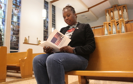 A person sits in a chapel and reads a booklet