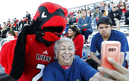 A woman take a selfie with Red the mascot