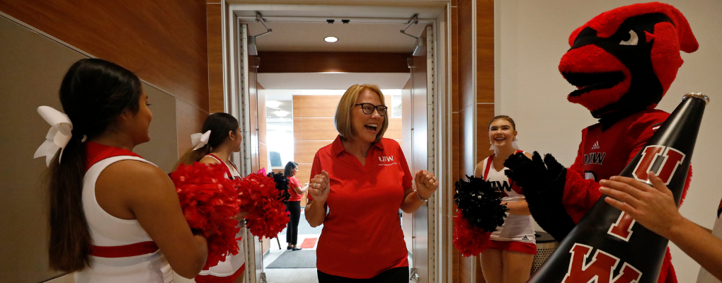 A woman is cheered on my cheerleaders and the UIW mascot