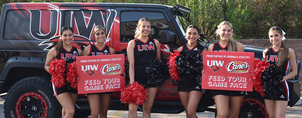 The UIW Spirit team stands in front of the UIW jeep holding spirit posters