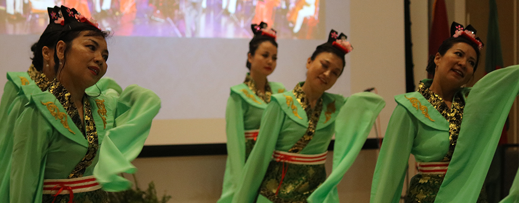 Women in traditional Asian attire perform a dance