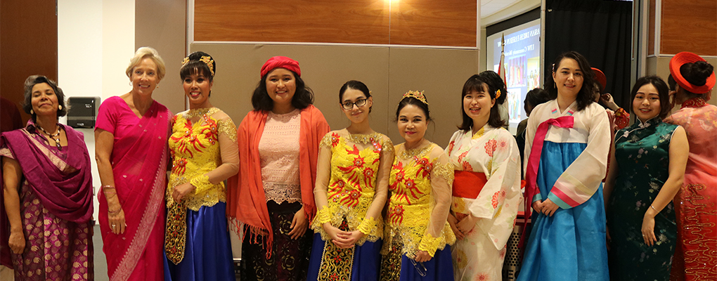 A group of women dressed in traditional Assian garments pose for a photo