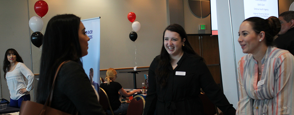 Three women talk at a career fair