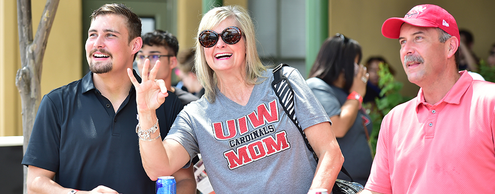 UIW fans smile and hold up the Cardinal sign