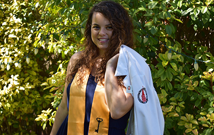 Chantelle Roman holds her white coat over her shoulder and smiles