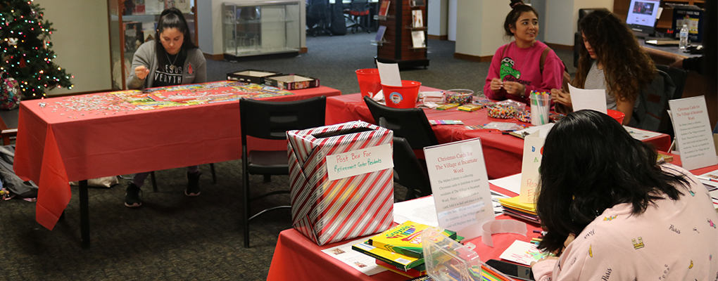 UIW students sit around a table and make Christmas cards