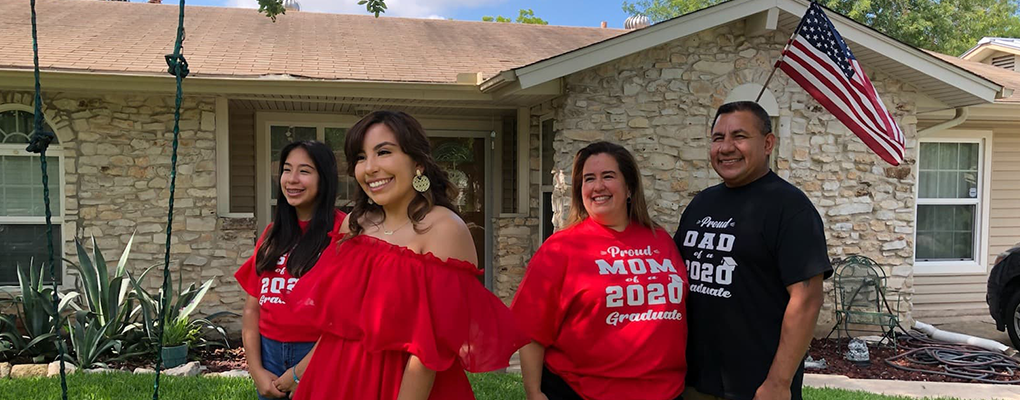 A family poses for a photo in front of their home