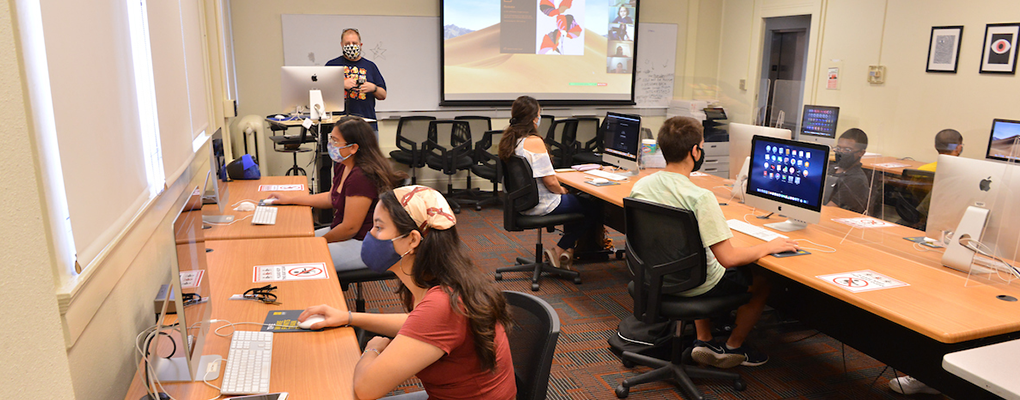 Students in masks sit in a computer lab