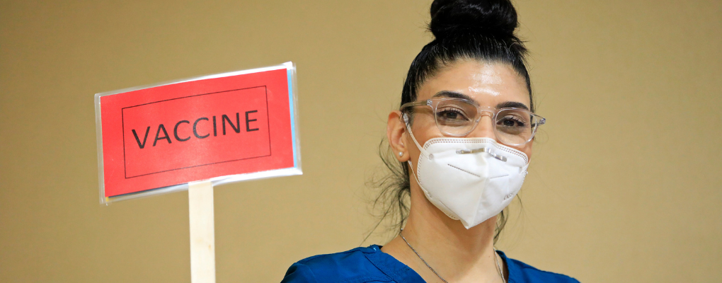 A nurse holds up a sign that says "vaccine"